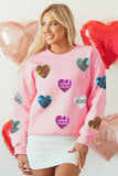 Woman wearing a pink sweatshirt with heart-shaped decorations in front of heart balloons.