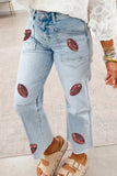 Light wash blue denim jeans with embroidered football patches on the thighs and lower legs, shown on a model wearing a white lace-trim top and beige slide sandals.