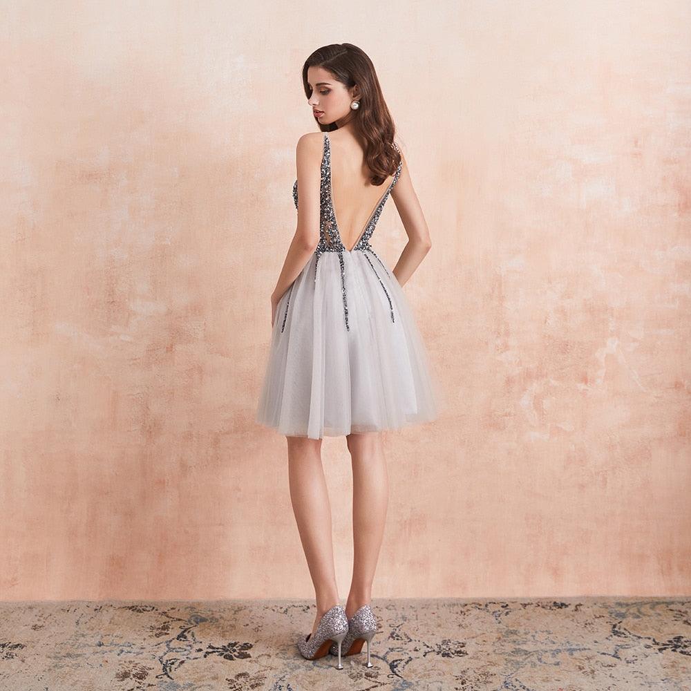 Woman wearing a silver dress with a textured back against a beige wall.