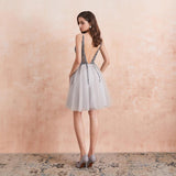Woman wearing a silver dress with a textured back against a beige wall.