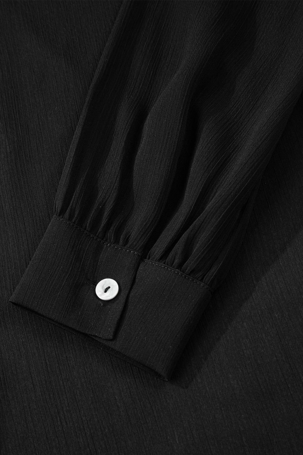 Close-up of a black shirt with a button on a black background
