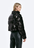 Person wearing a black sequin puffer jacket on a white background
