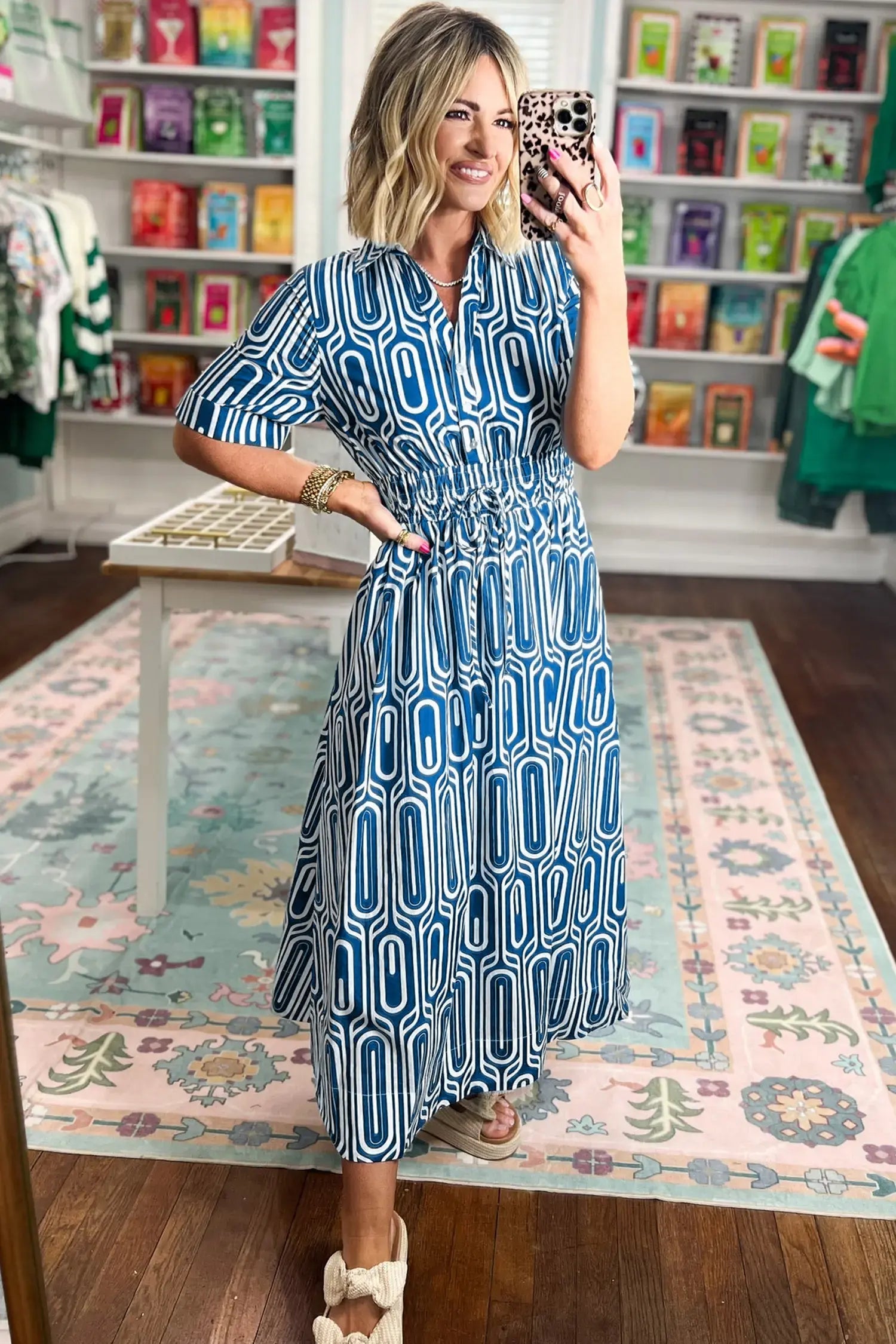 Woman taking a selfie in a patterned dress in a store.
