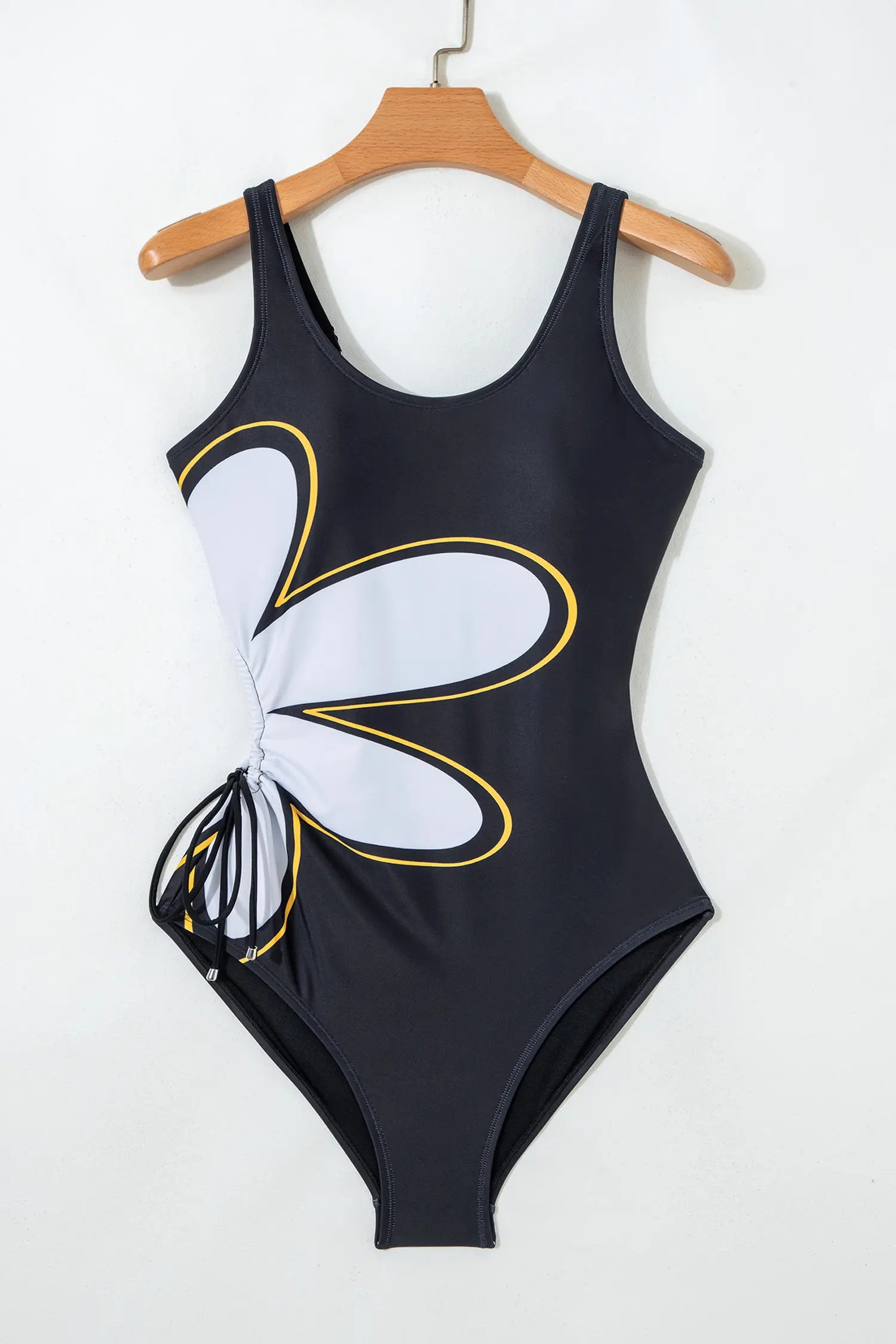 Black swimsuit with white and yellow floral design on a hanger against a white background