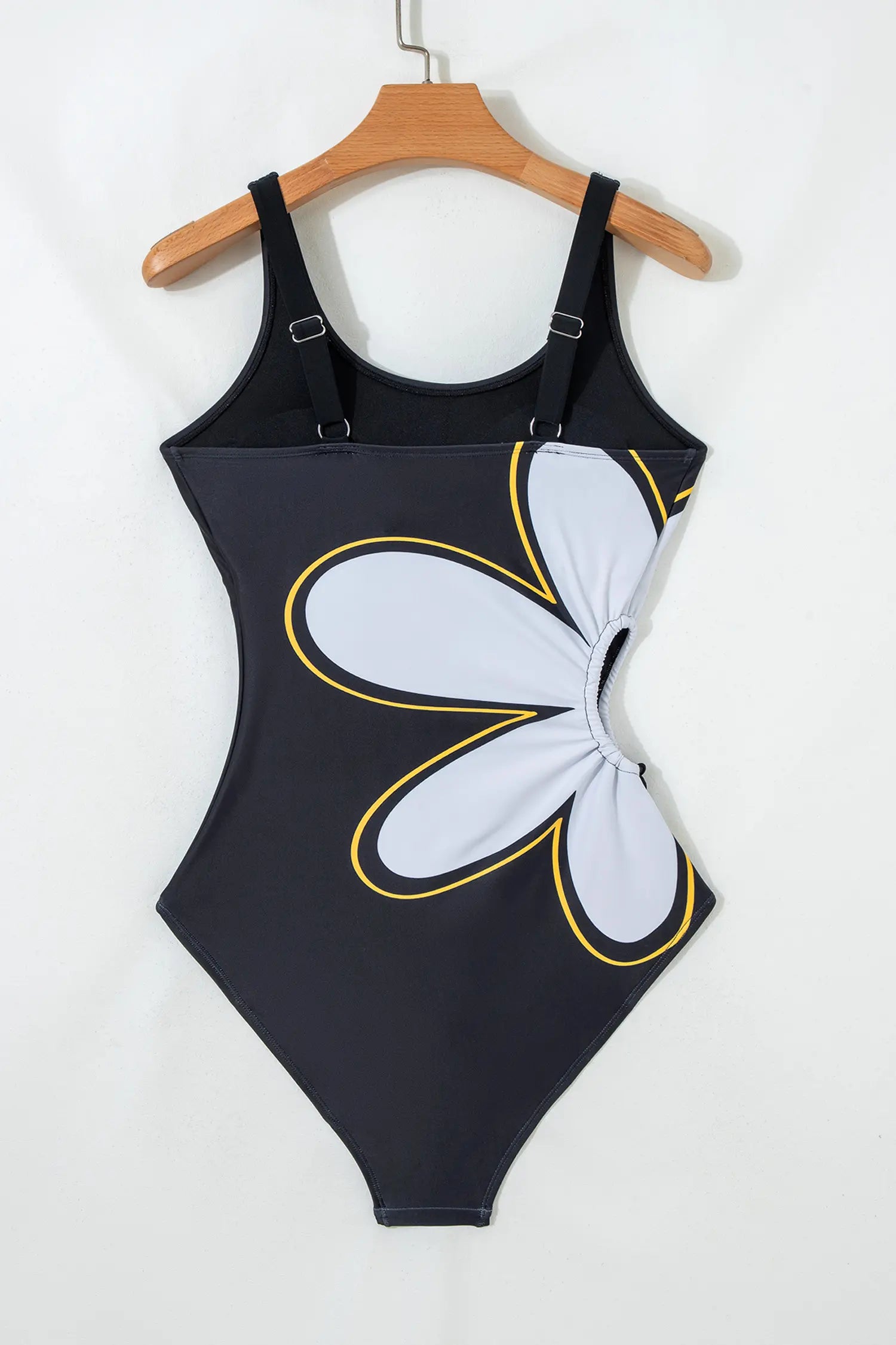 Black swimsuit with a white floral design on a hanger against a white background