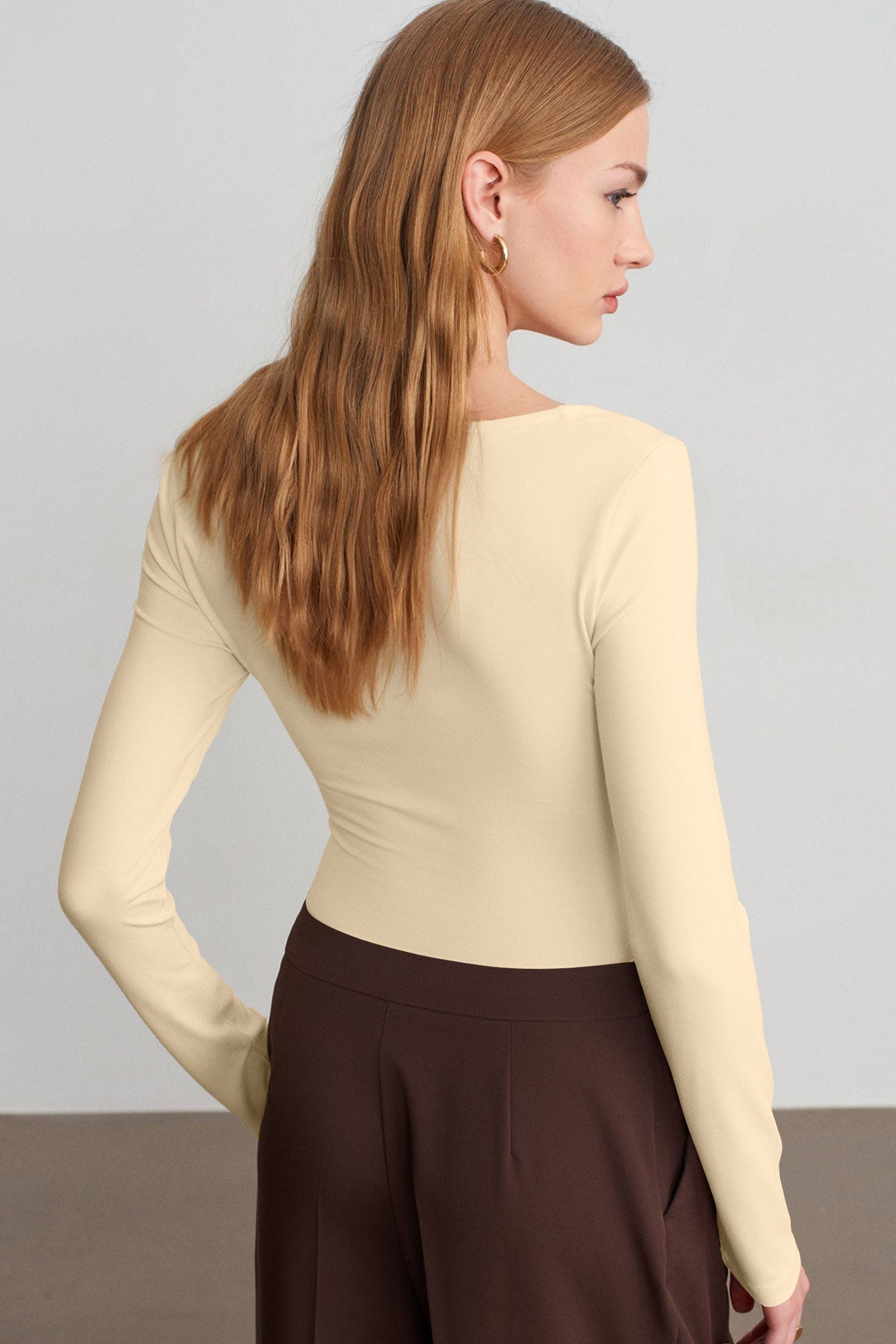 Back view of woman in fitted cream top with dark brown wide-leg trousers.