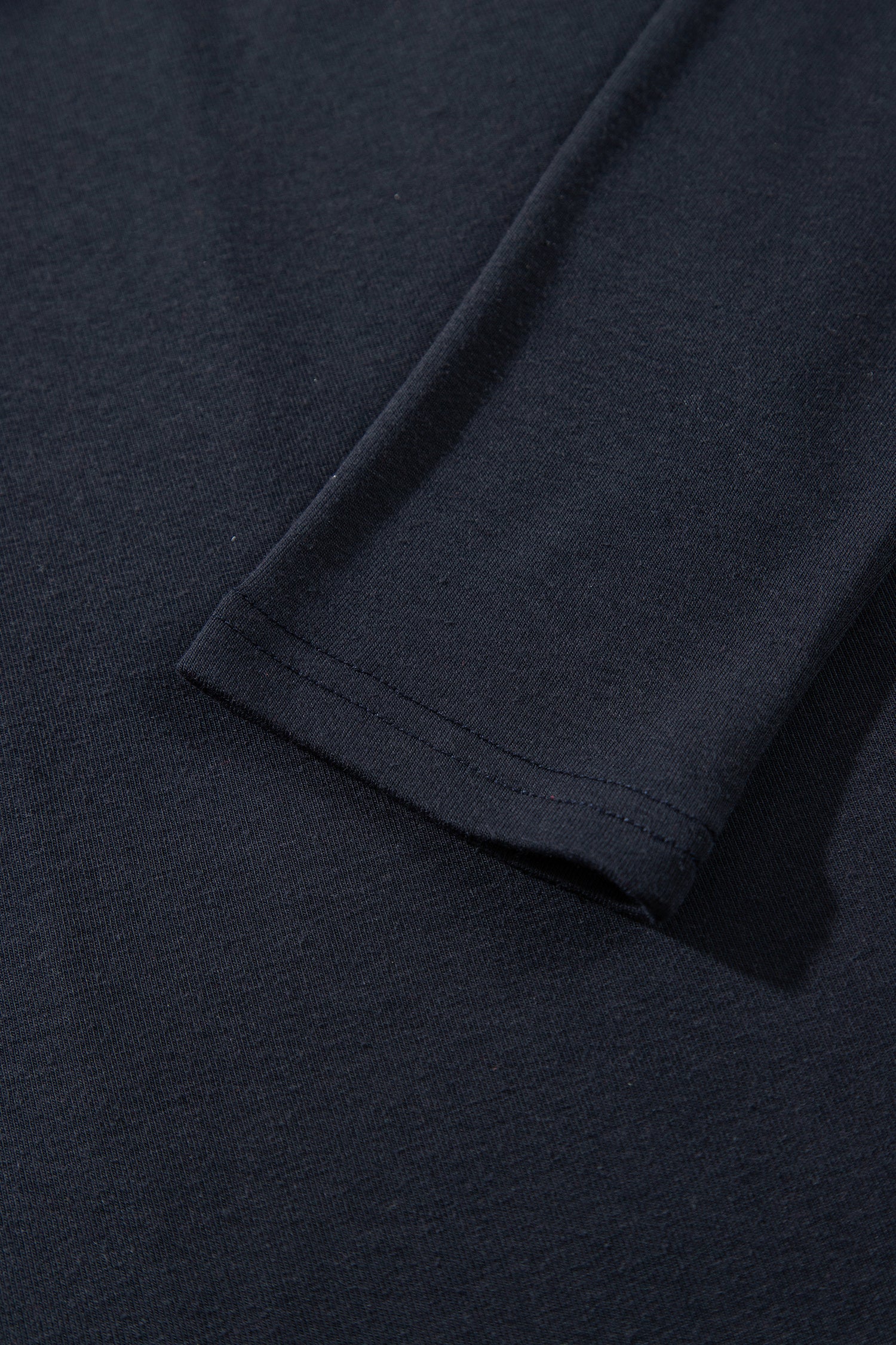 Close-up of a dark navy blue fabric sleeve cuff with neat hem stitching.