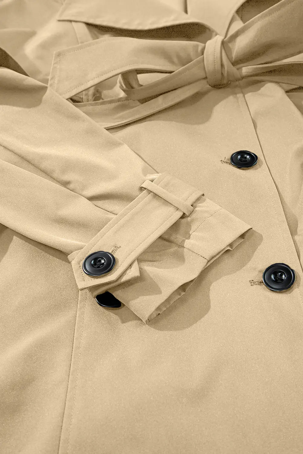 Close-up of a beige trench coat with black buttons