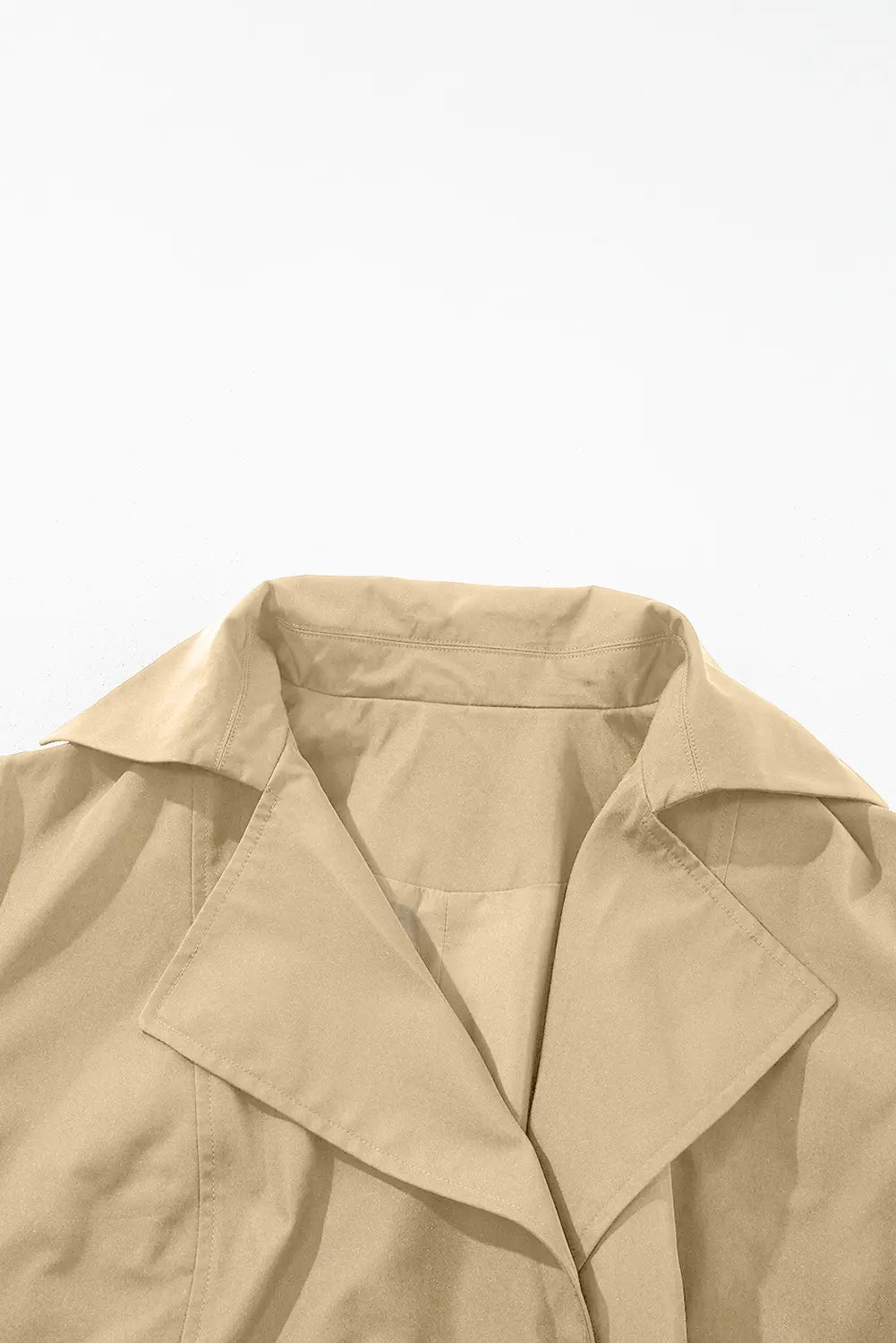 Close-up of a beige trench coat on a light gray background