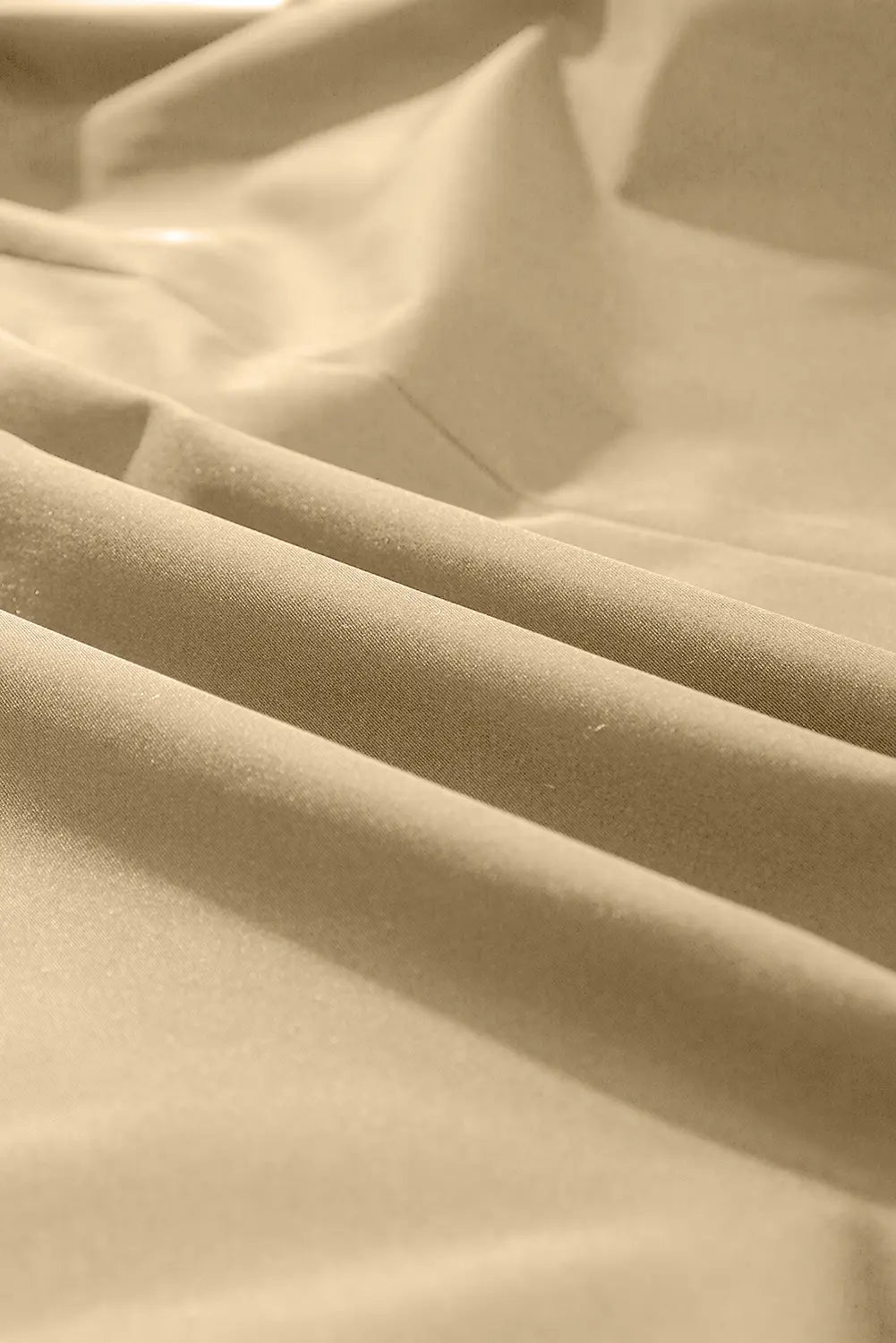 Close-up of draped beige fabric with soft folds and a smooth texture.