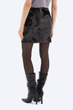 Person wearing a black sequin skirt and black high-heeled boots on a white background