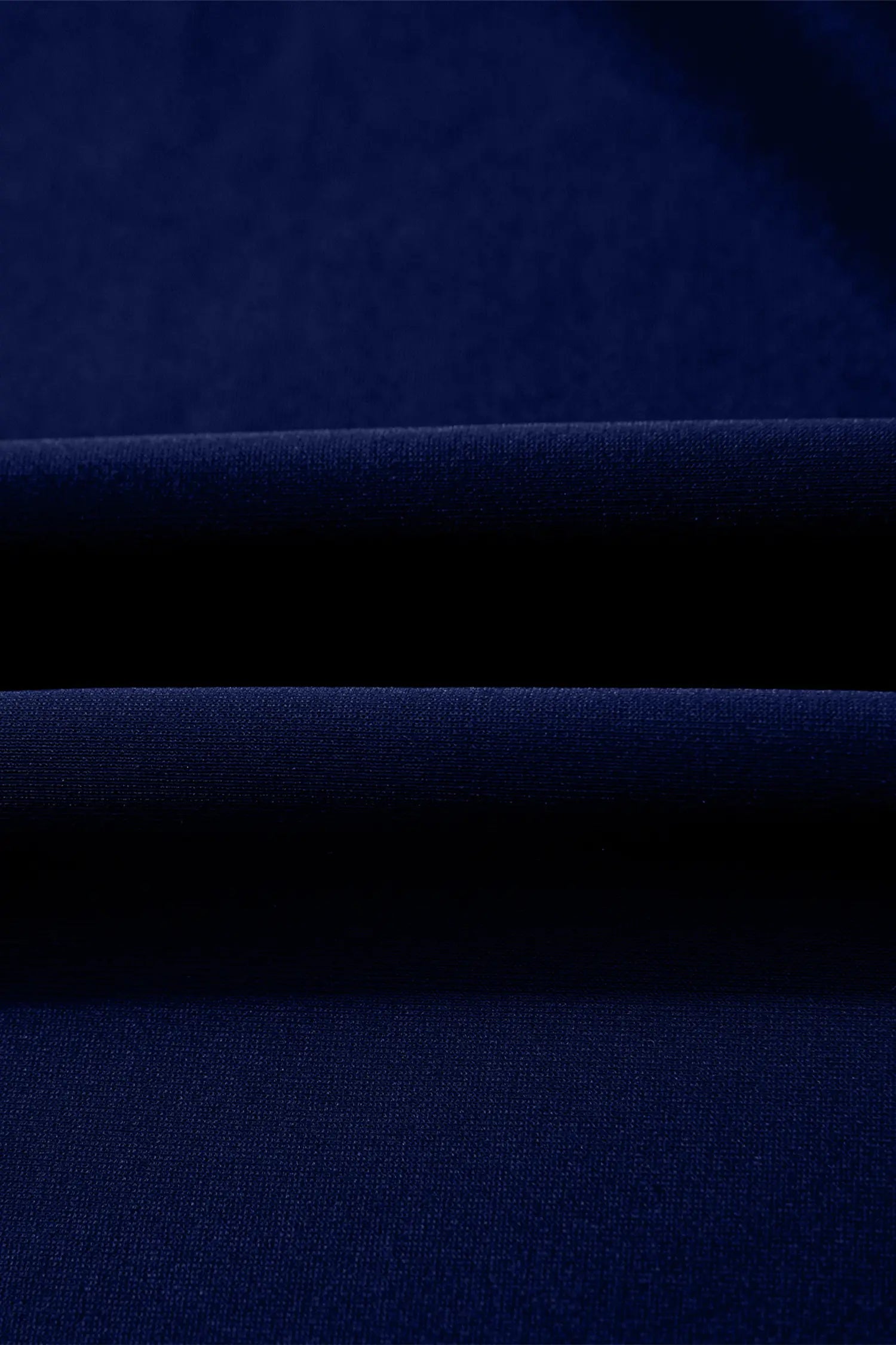 A close-up of dark navy blue fabric with soft horizontal folds showing the texture and color.