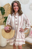A woman wearing a light pink and cream striped linen shirt dress, holding a woven straw handbag with a wooden handle in a bright, modern room.