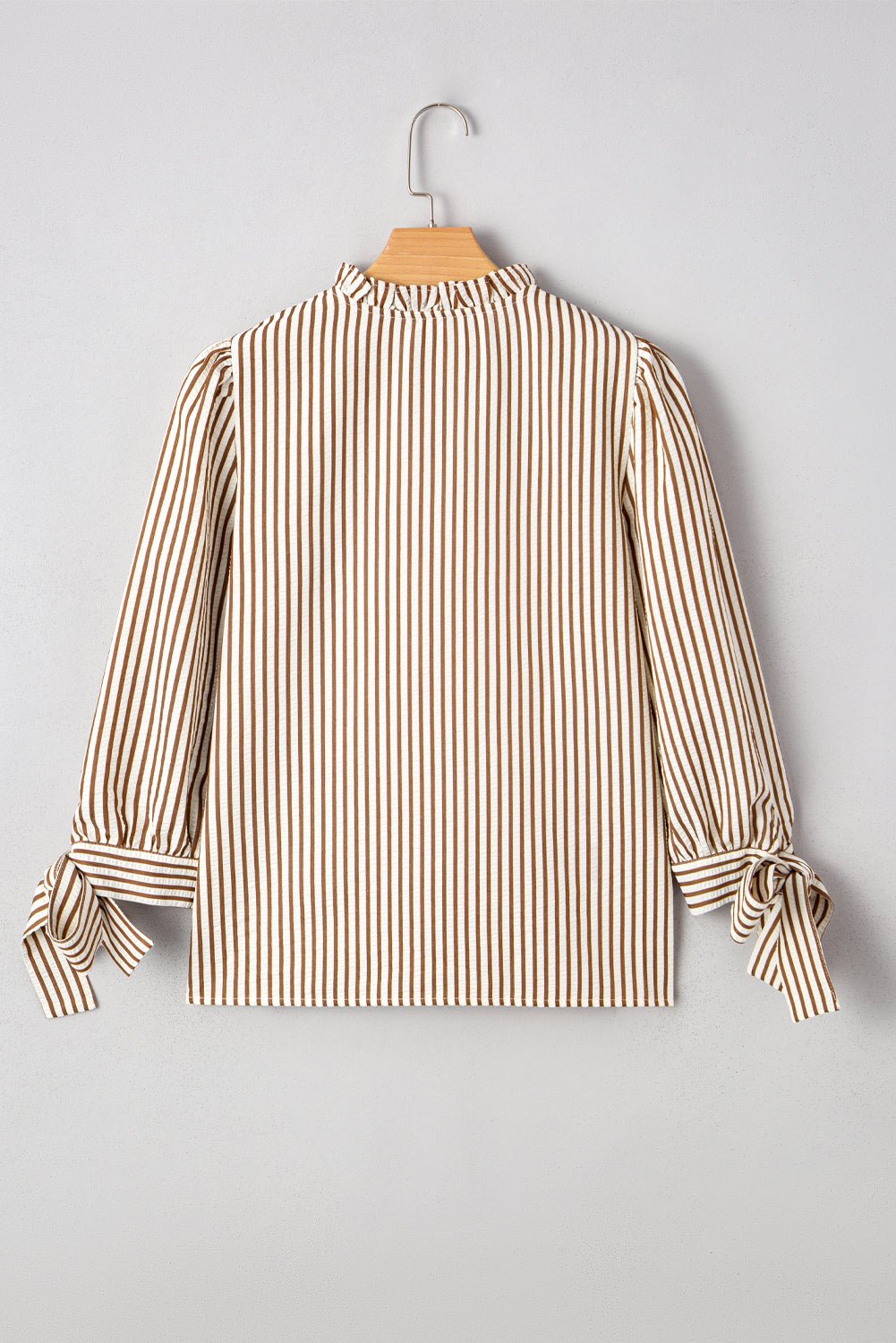 Striped blouse on a hanger against a gray background