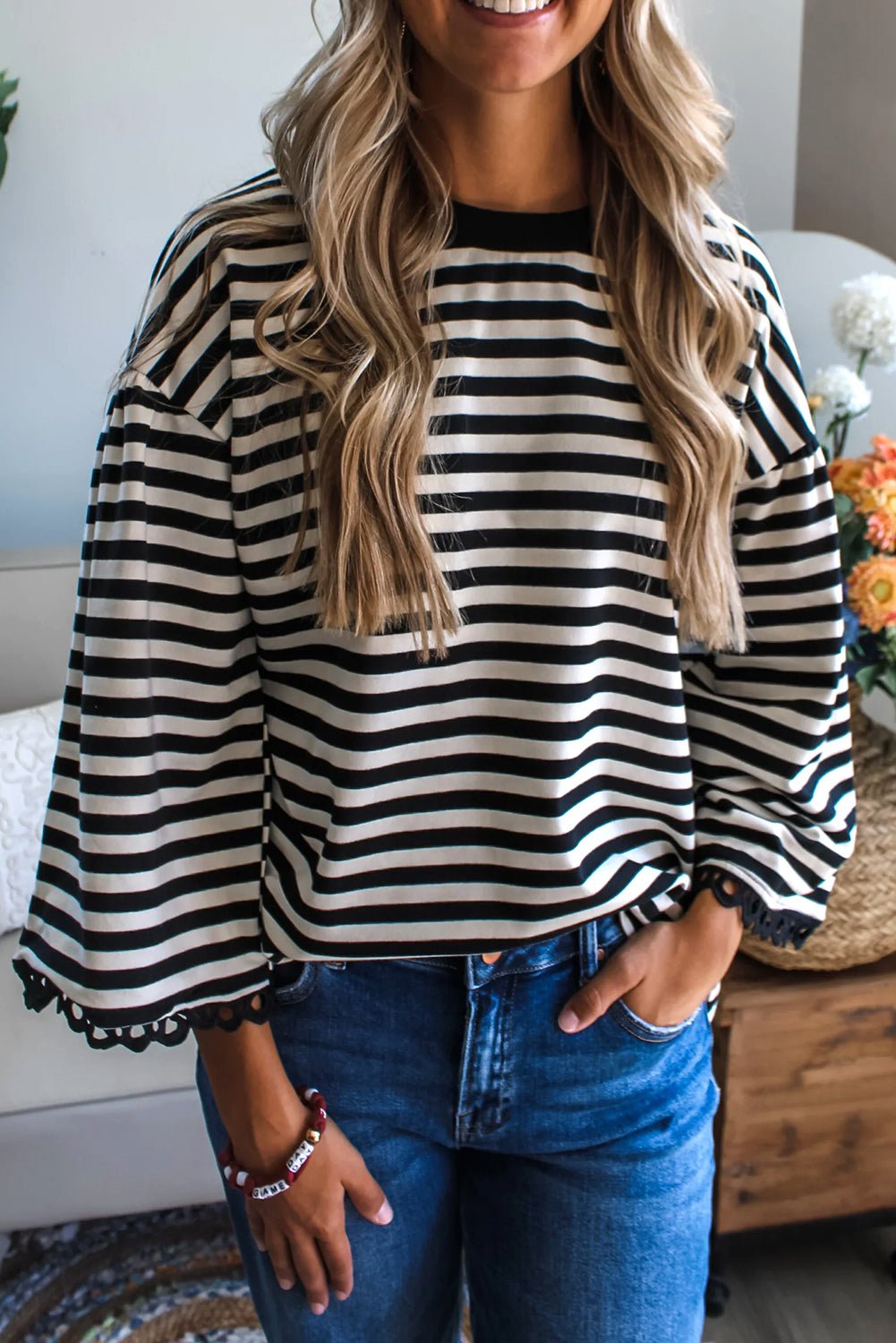 Woman wearing a black and white striped shirt with blue jeans indoors.