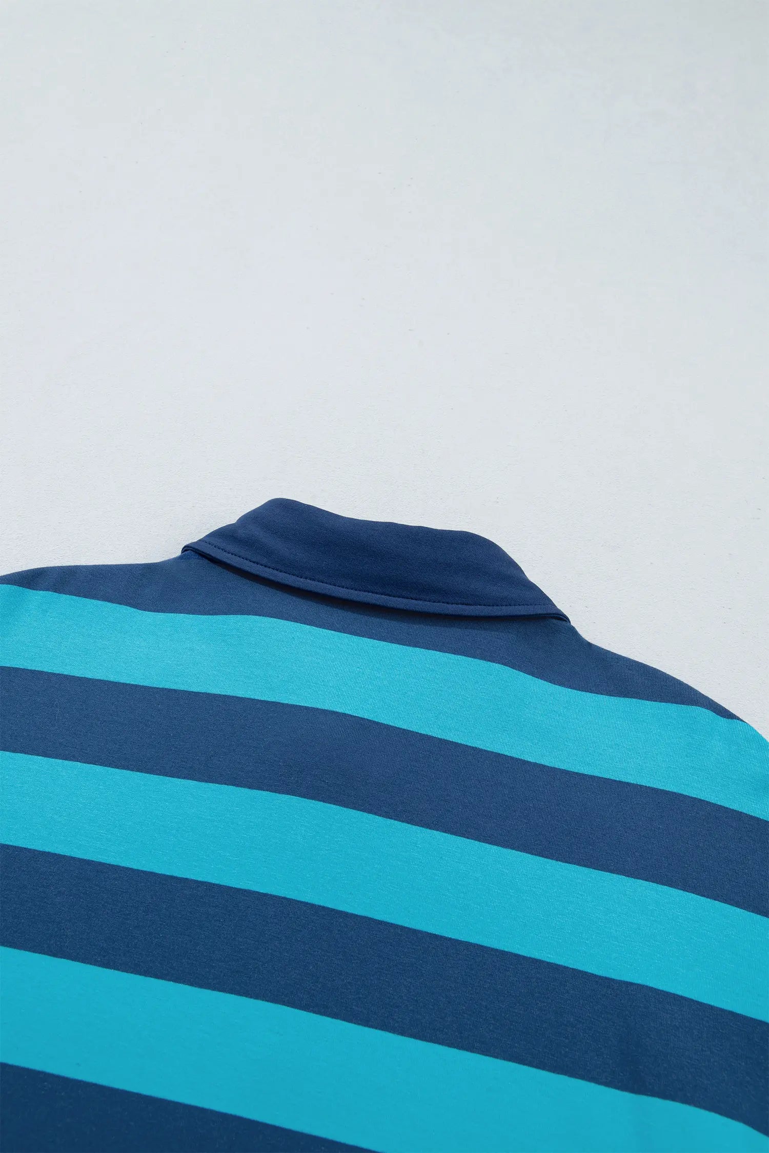 Close-up back of navy and turquoise striped polo shirt with collar.