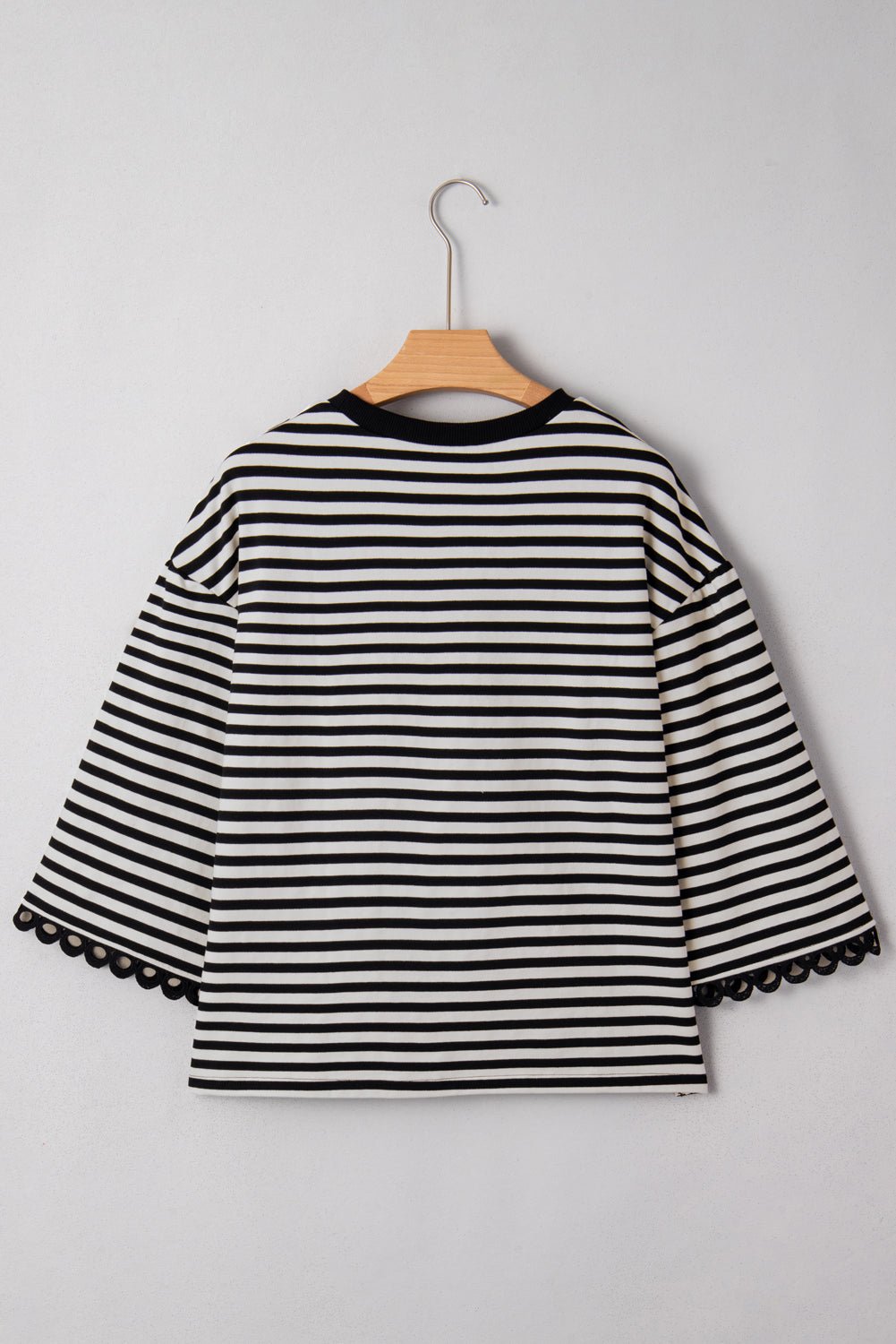 Black and white striped shirt on a hanger against a gray background