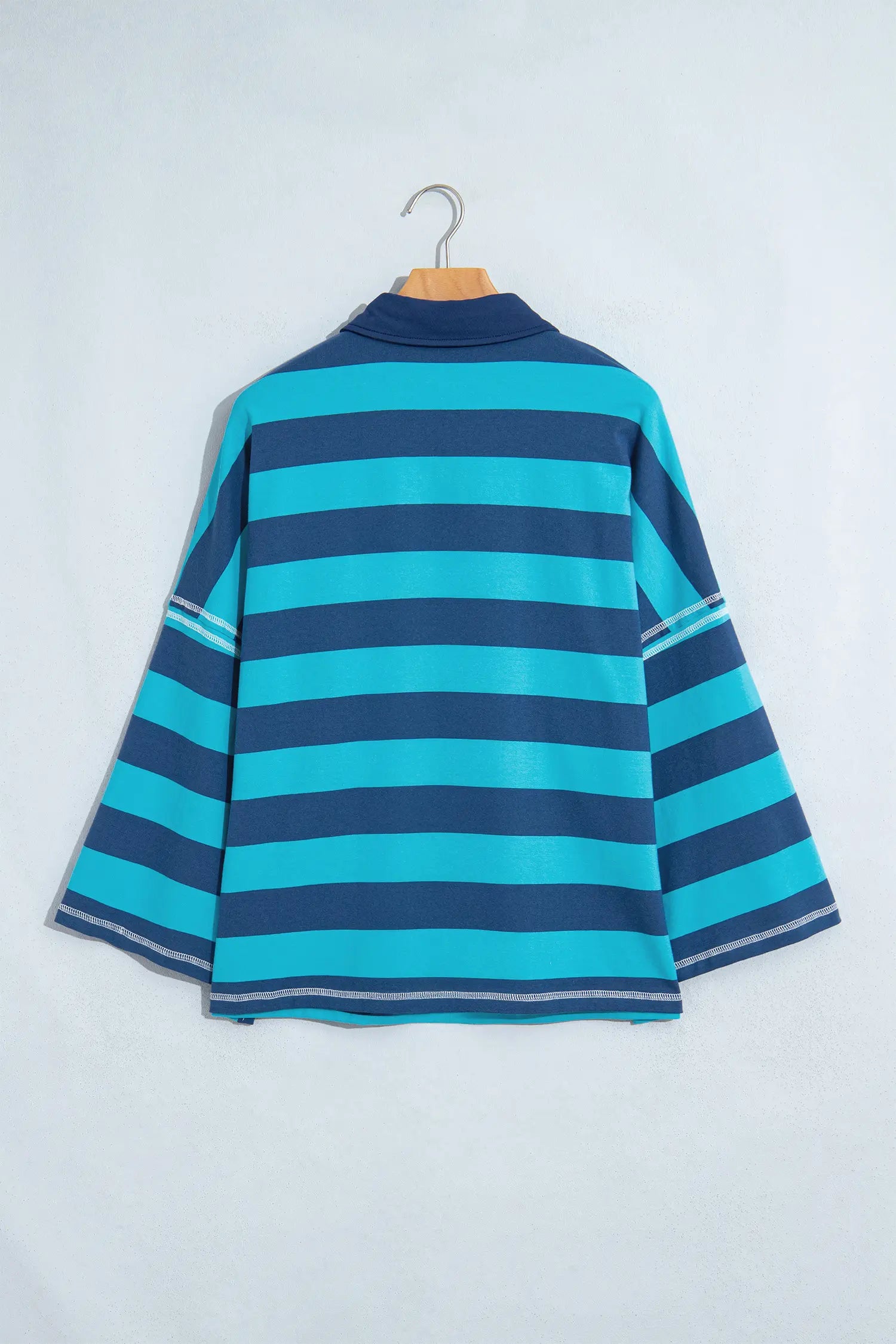 Navy-turquoise striped mock-neck top with solid navy collar on hanger.