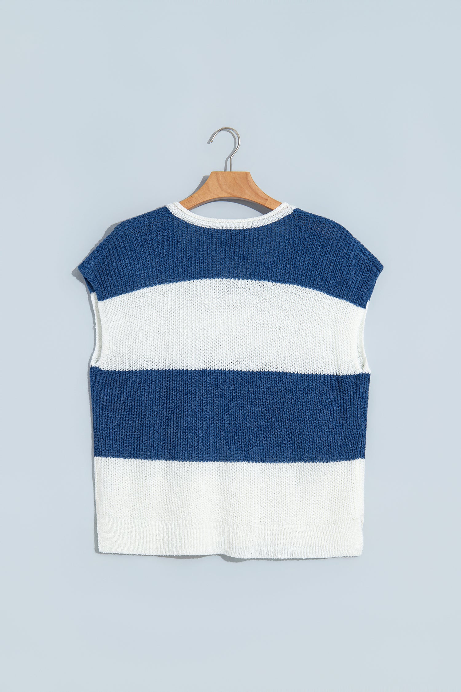 A sleeveless knit top with horizontal navy blue and white stripes, hanging on a wooden hanger against a light blue-gray background.