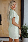 Woman wearing a green and white striped dress standing in front of a wooden door.
