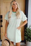 Woman wearing a green and white striped dress standing in front of a wooden door.