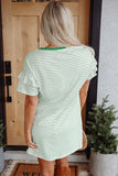 Person wearing a green and white striped dress standing in front of a wooden door.