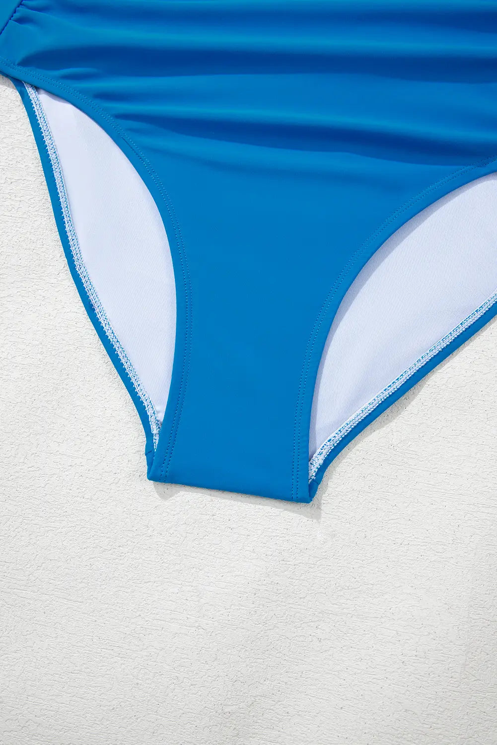 Blue bikini bottom with white trim on a light gray background