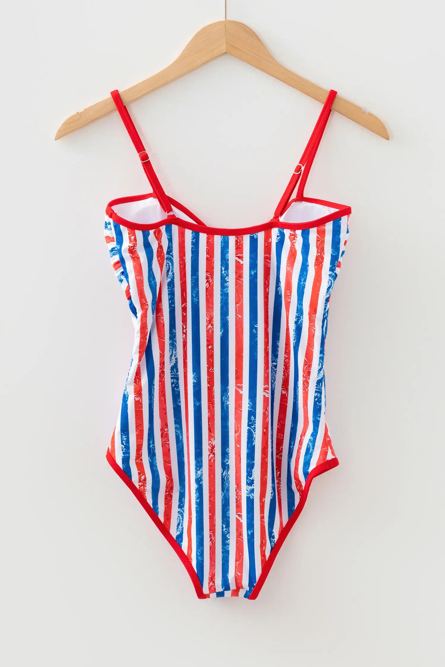 Red, white, and blue striped swimsuit on a hanger against a white background
