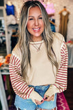 Woman wearing a beige and red striped long-sleeve shirt with denim shorts in a store setting.
