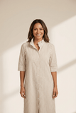 Woman wearing a beige and white striped dress against a neutral background