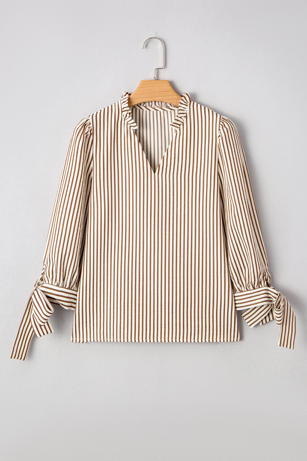 Striped blouse on a hanger against a gray background