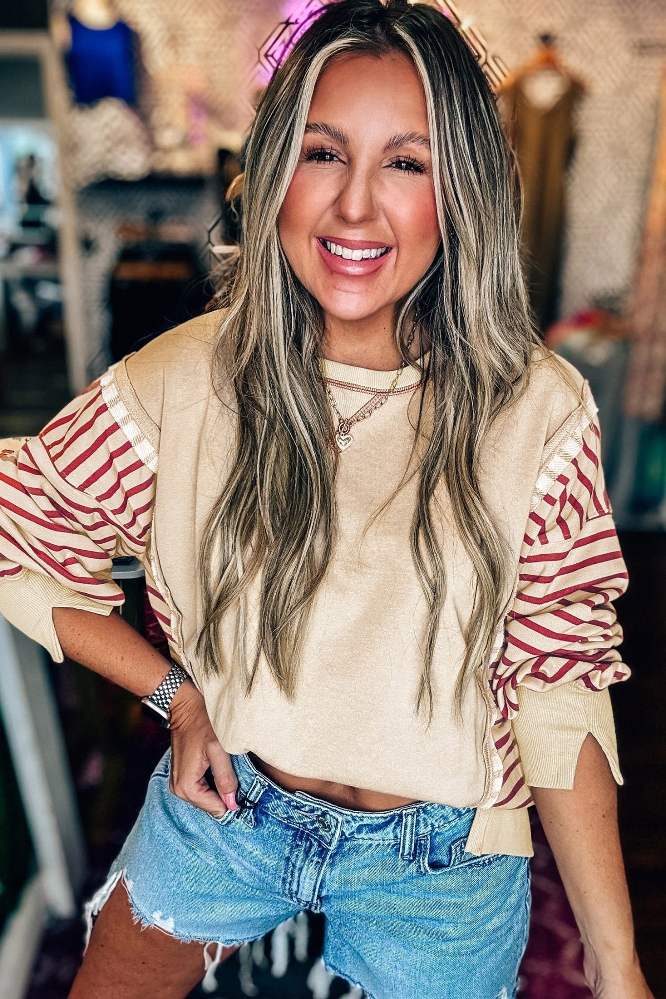 Woman wearing a beige and red striped shirt with denim shorts in an indoor setting