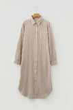 A long-sleeve button-front shirt dress with vertical brown and beige stripes, featuring a single chest pocket, shown hanging on a wooden hanger against a light gray background.