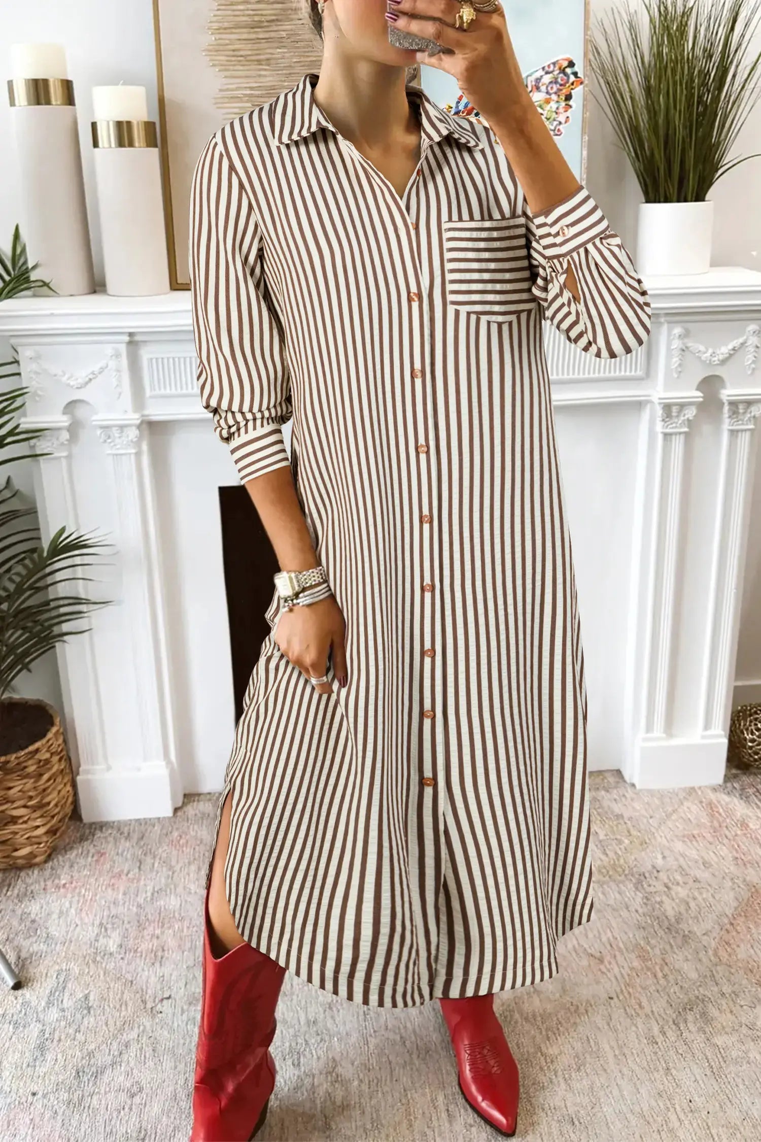 Person wearing a long striped shirt dress with red shoes in a home setting.