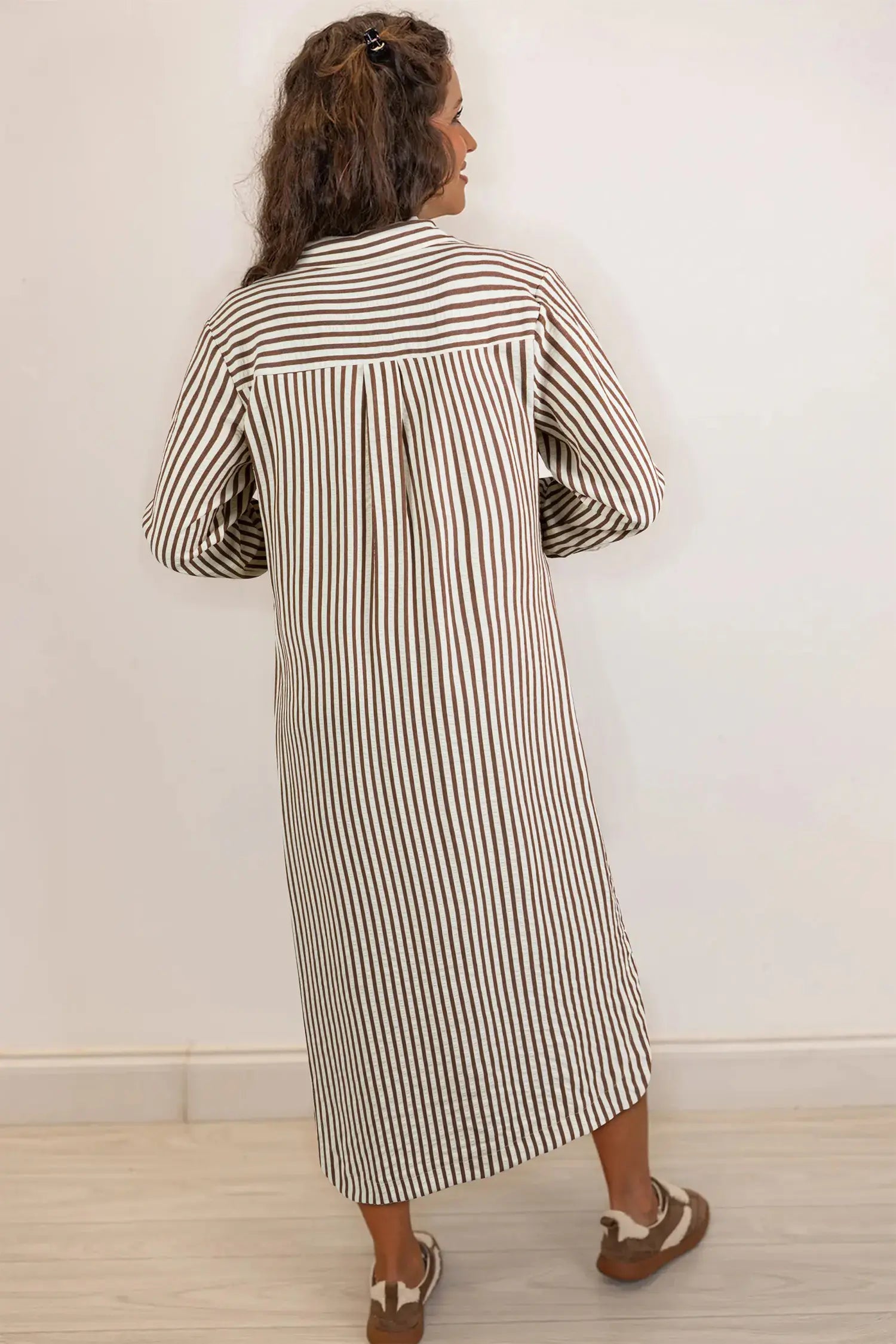 Woman wearing a long black and white striped dress against a plain background