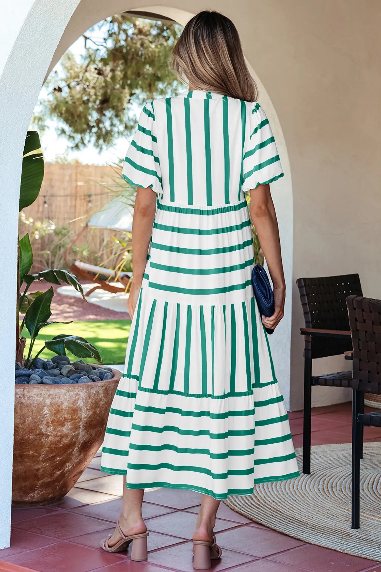 Woman wearing a green and white striped dress in an outdoor setting.