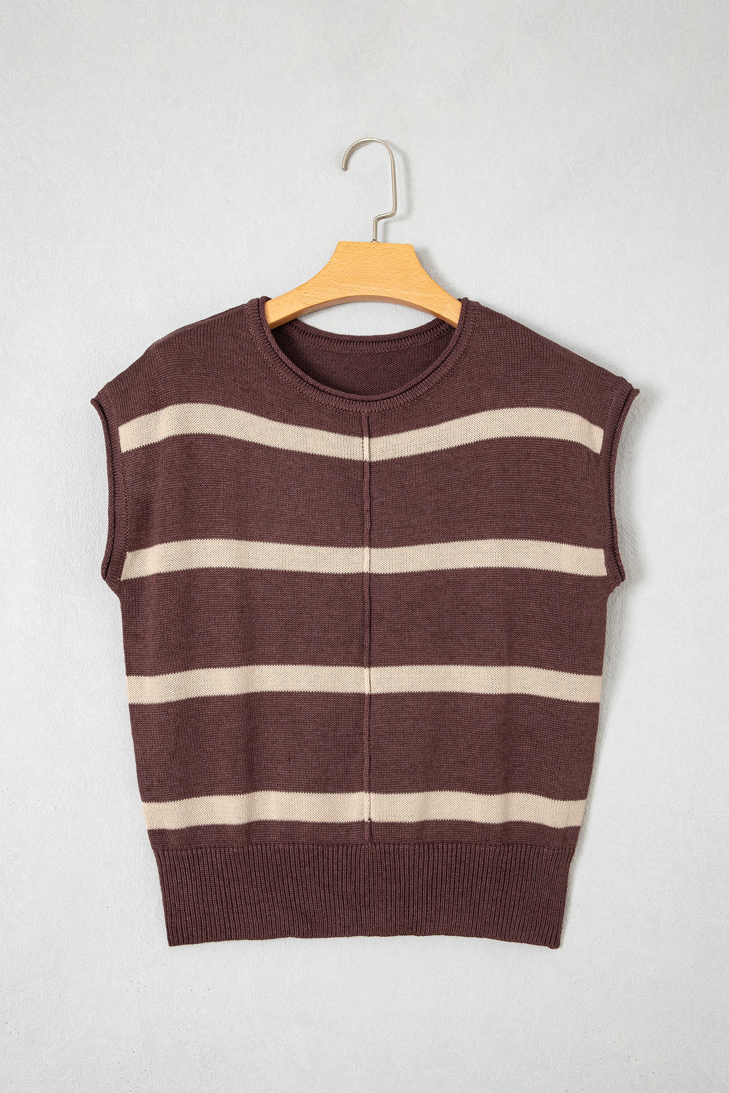 A sleeveless knit sweater vest with horizontal stripes in dark brown and cream, hanging on a wooden hanger against a light gray background.