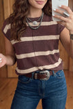 A woman wearing a brown and beige horizontally striped knit top, paired with a brown leather belt with a silver buckle and blue jeans, taking a mirror selfie.