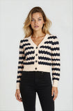 Woman wearing a black and white striped cardigan on a plain background