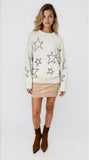 Woman wearing a cream sweater with star patterns on a white background
