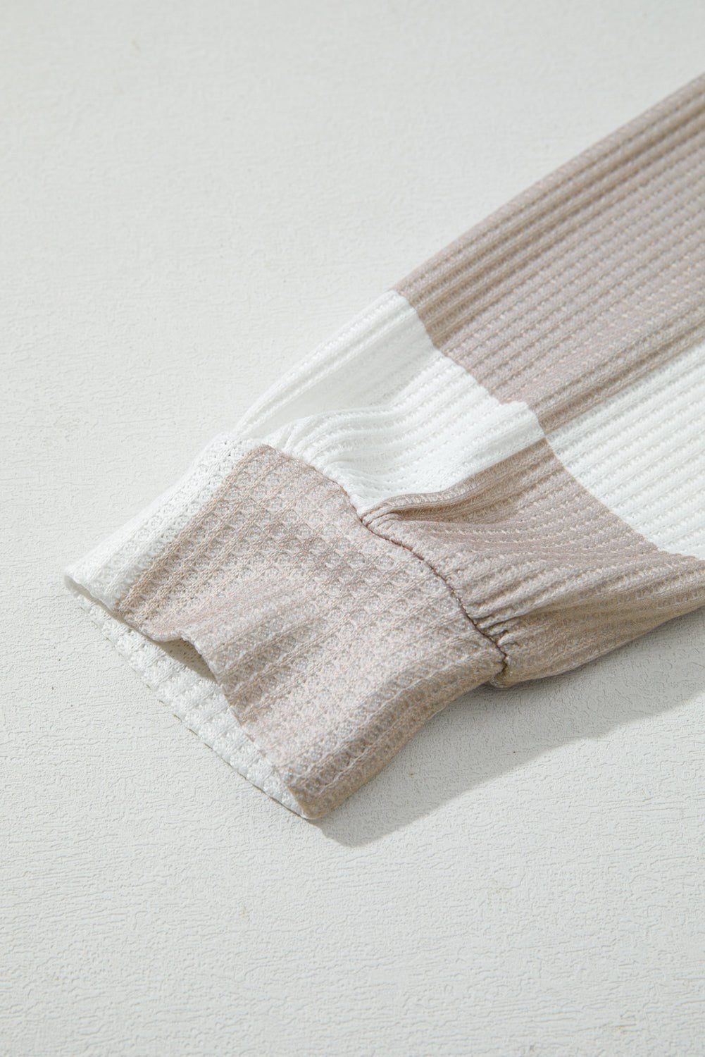 Close-up of a folded towel with beige and white stripes on a light gray background