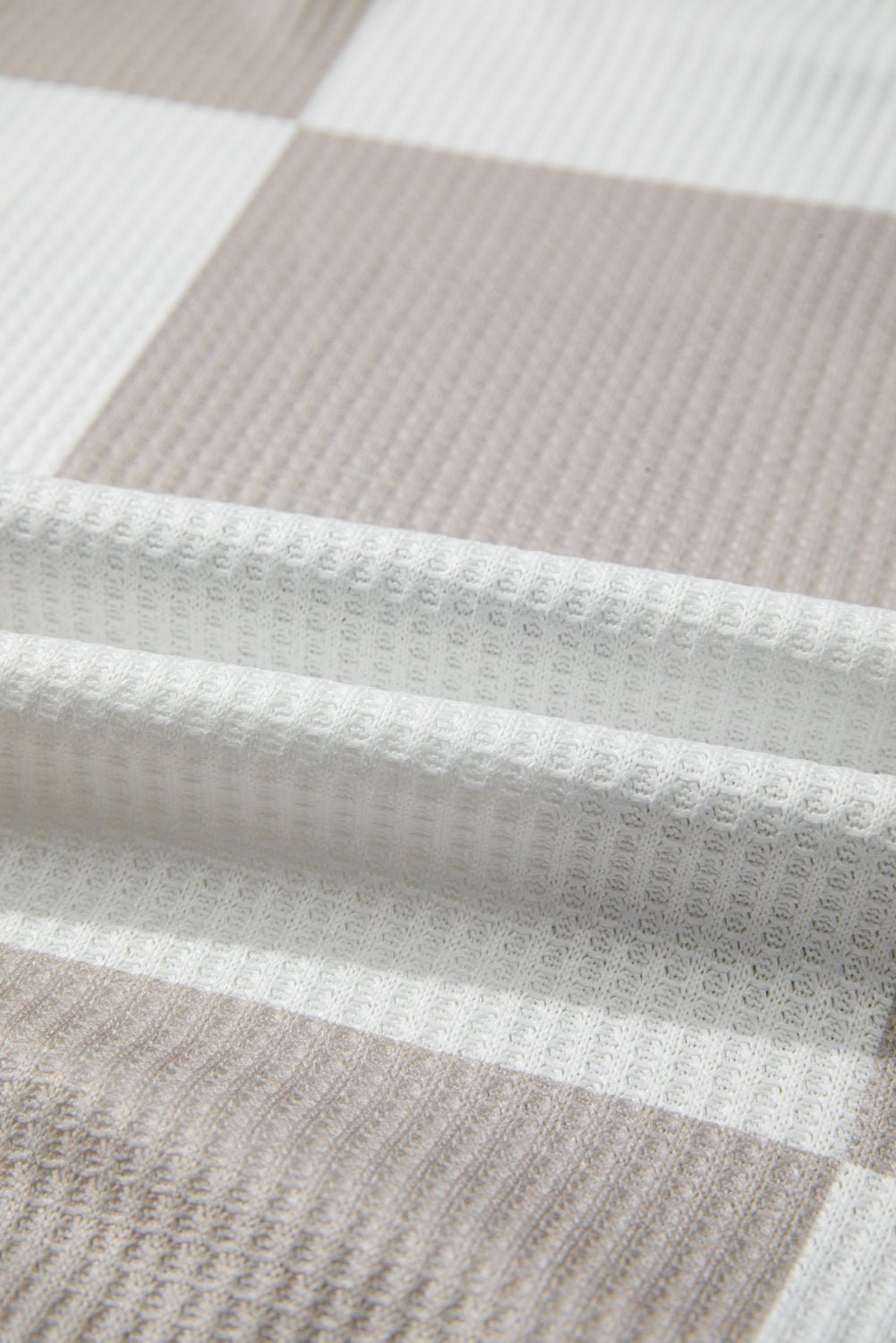 Close-up of a textured fabric with a checkered pattern in neutral colors.