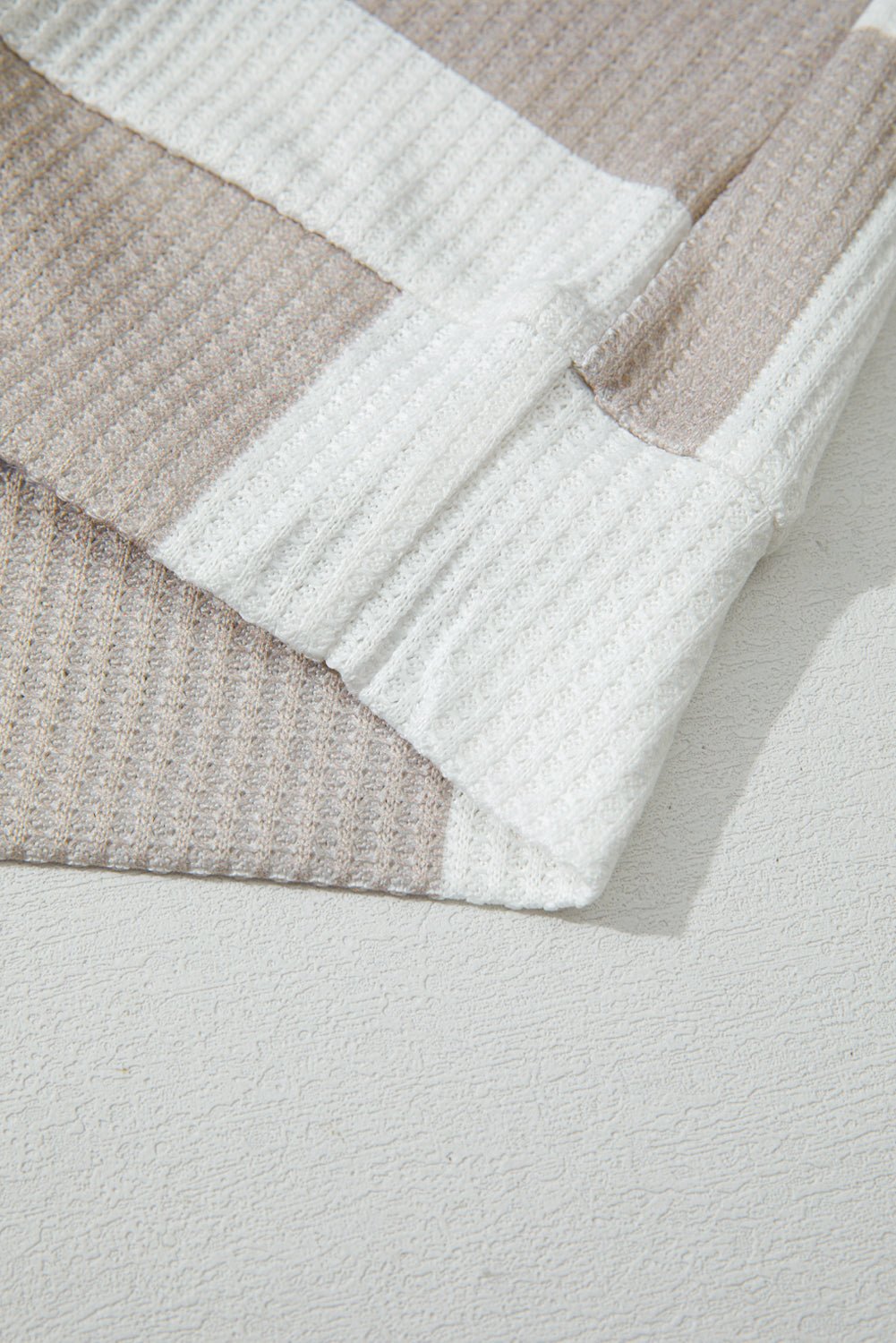 Close-up of a textured blanket with geometric pattern on a light gray background
