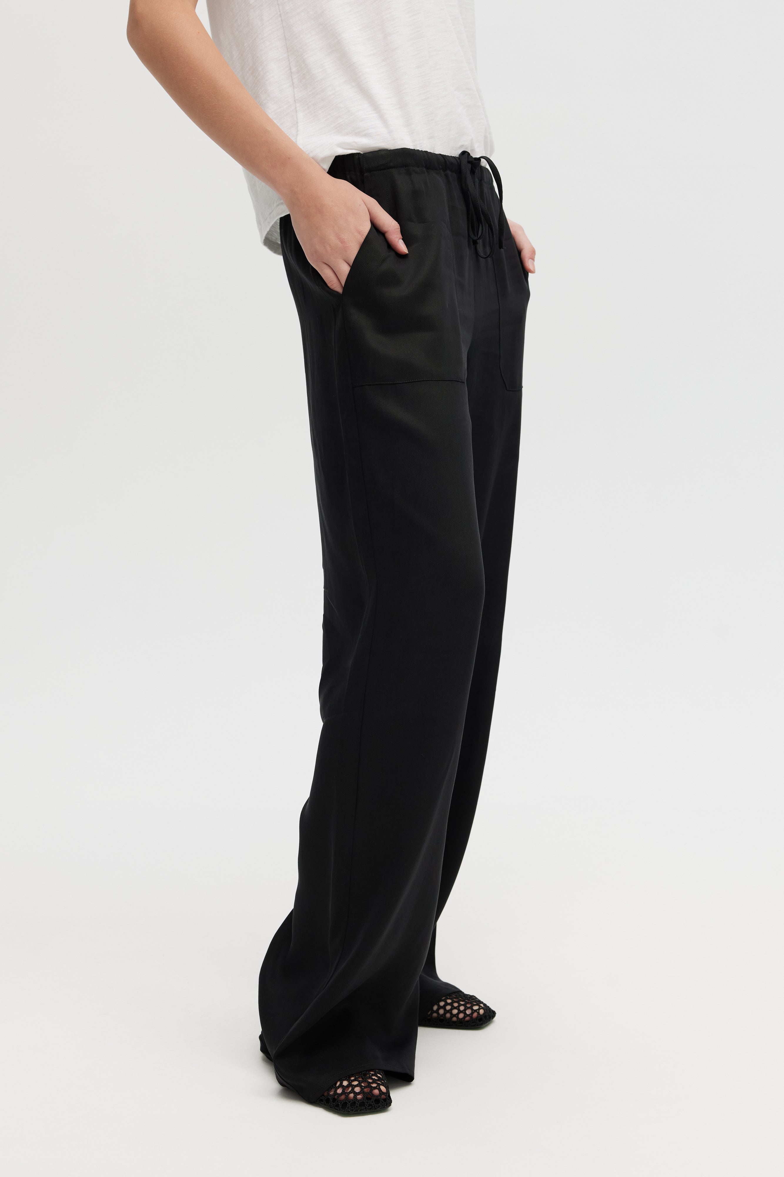 Person wearing black wide-leg pants on a white background