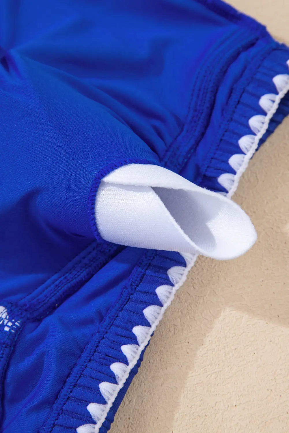 Blue swimsuit with white trim on a beige background