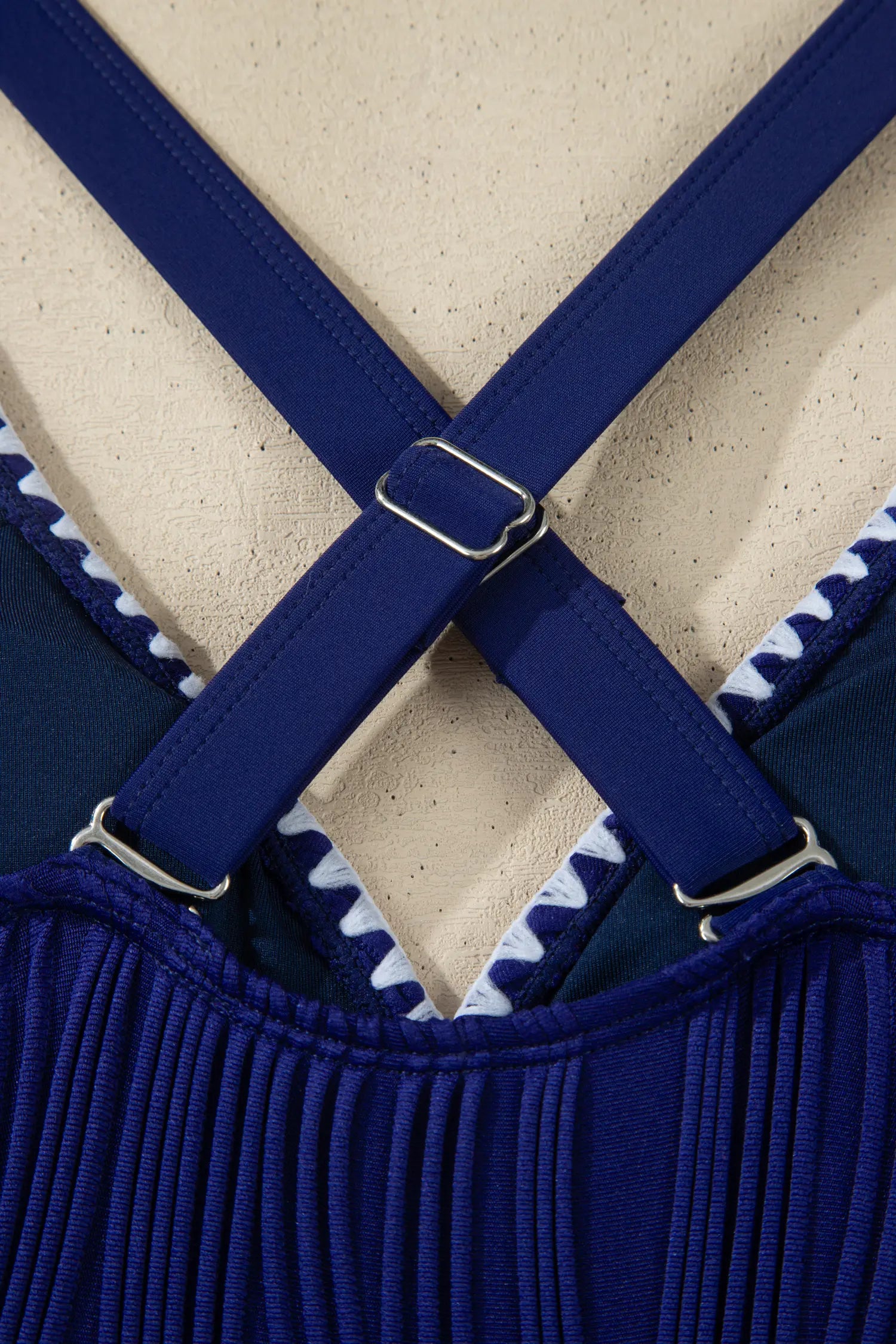 Close-up of blue suspenders with a textured beige background