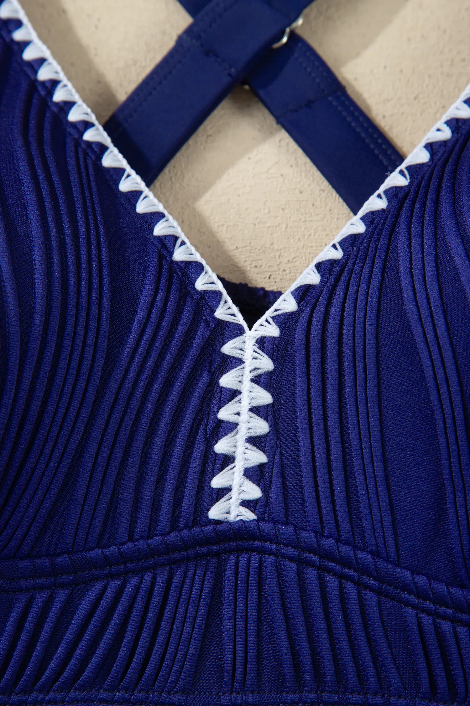 Close-up of a blue ribbed garment with white trim on a beige background