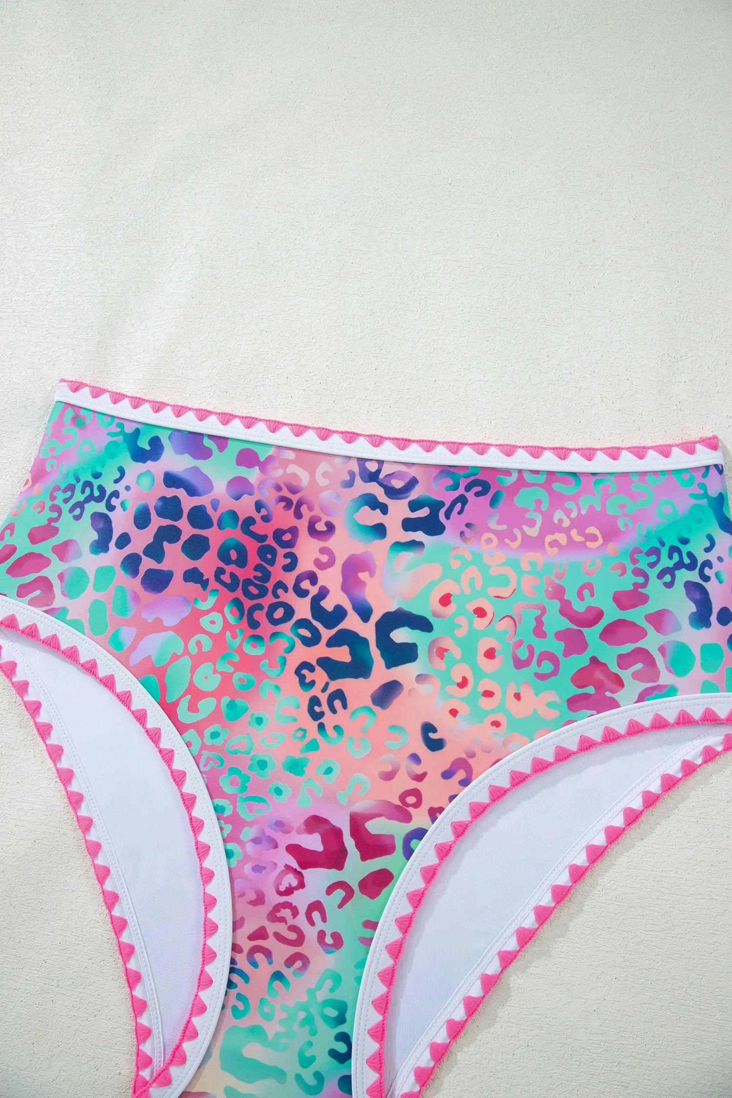 Colorful leopard print bikini bottom with pink trim on a white background