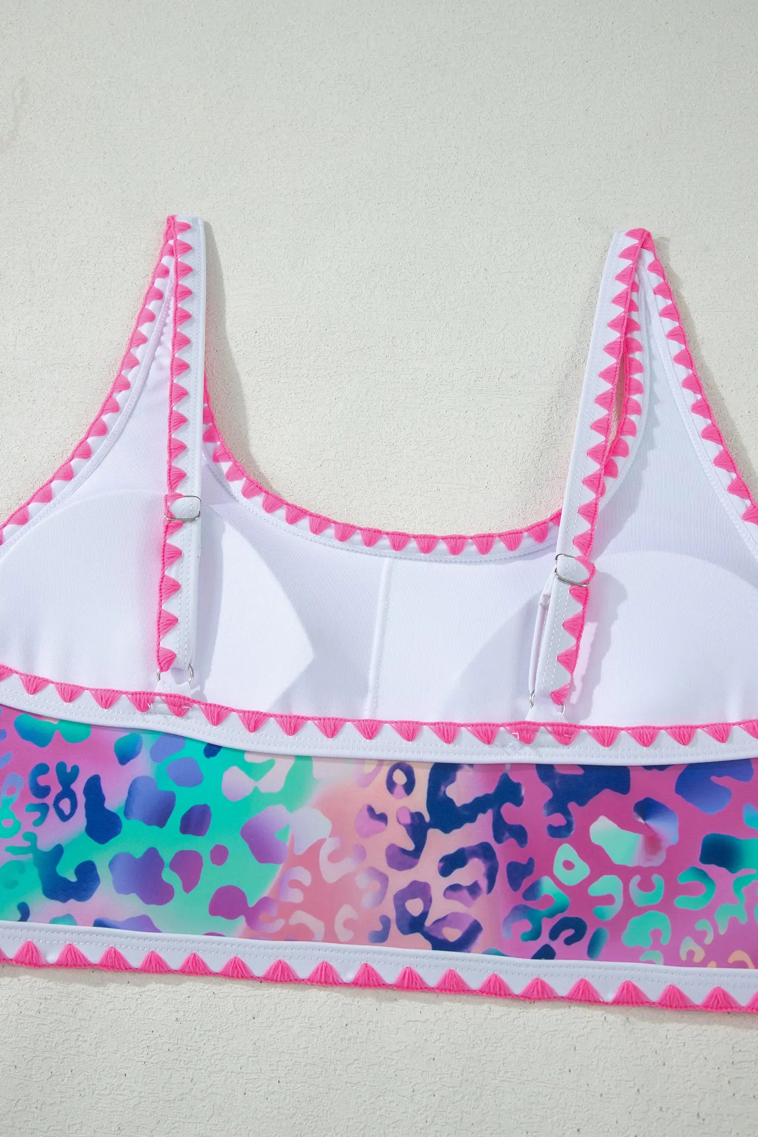 White bikini top with colorful leopard print trim on a white background