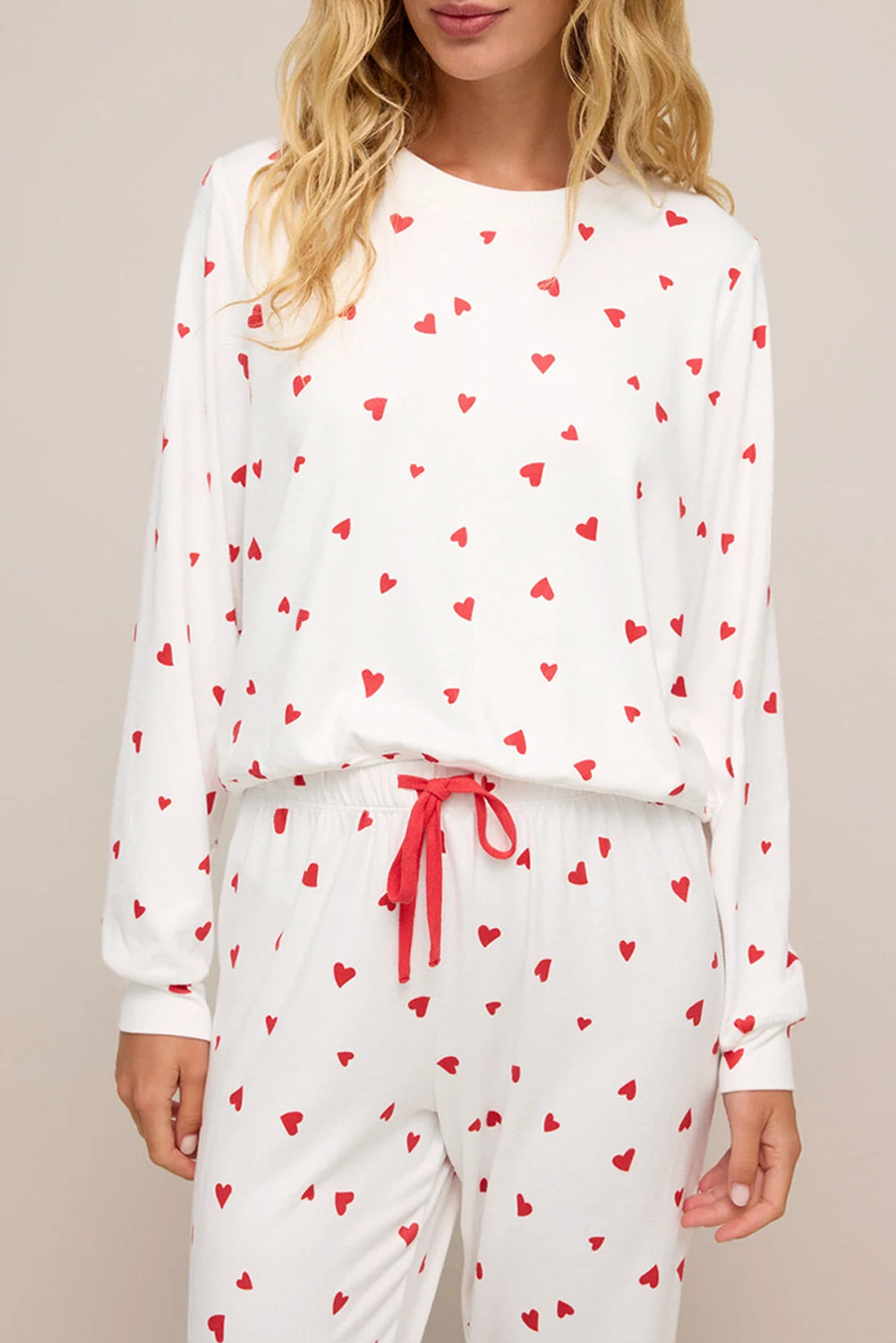 White pajama set with red heart patterns on a neutral background